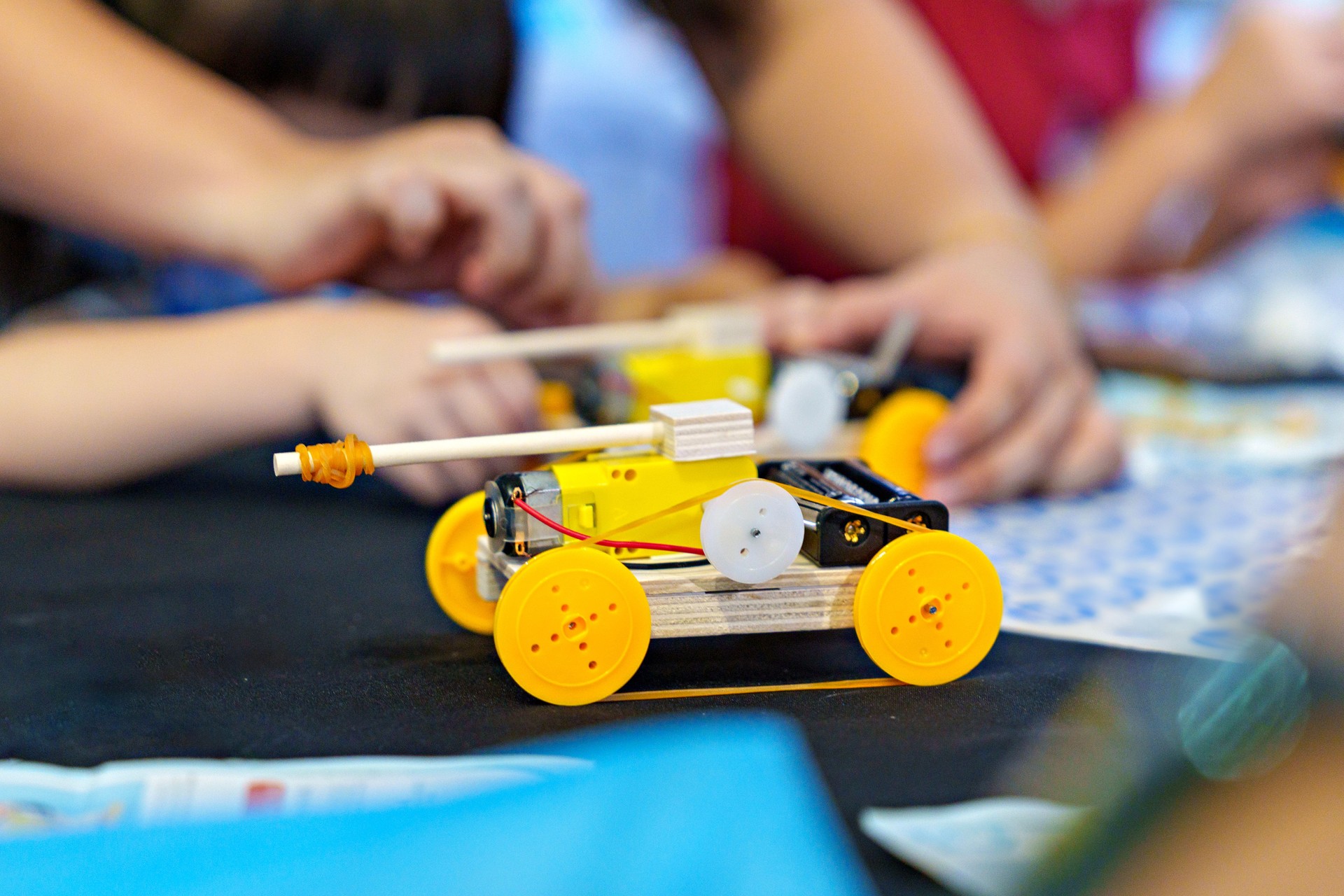 The close-up view showcases a student diligently working on a DIY robotic car, capturing the essence of coding, technology, robotics, and science.